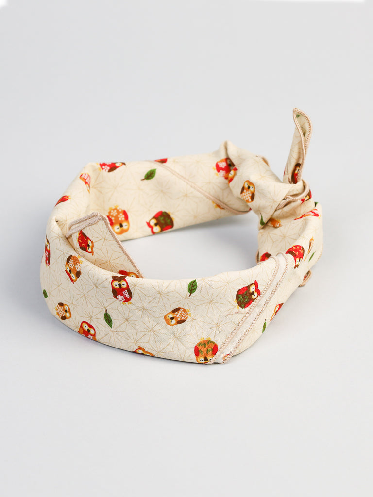 The Japanese Owl Bandana by ID Menswear is crafted from 100% cotton with cream-colored fabric, featuring vibrant red and orange owl designs and small green leaves, artfully knotted on a light gray background.