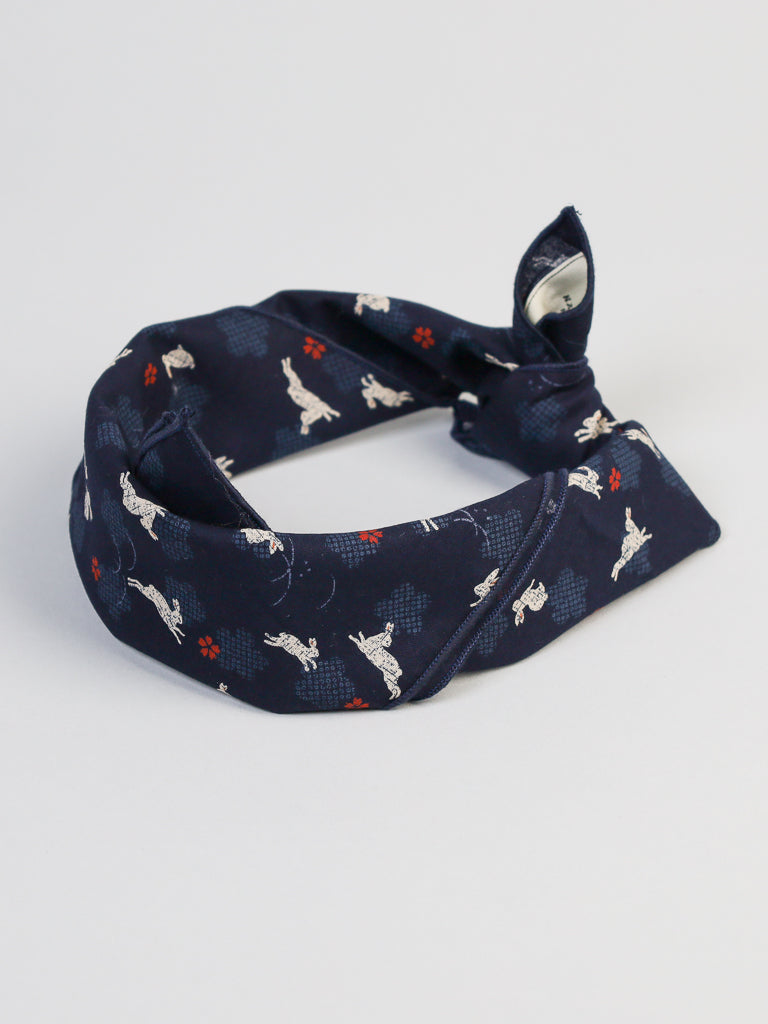 Introducing ID Menswears Bunnies and Blossoms Bandana, a cotton piece with embroidered white rabbits and vibrant cherry blossoms, elegantly tied in a neat knot to stand out against a simple light background.