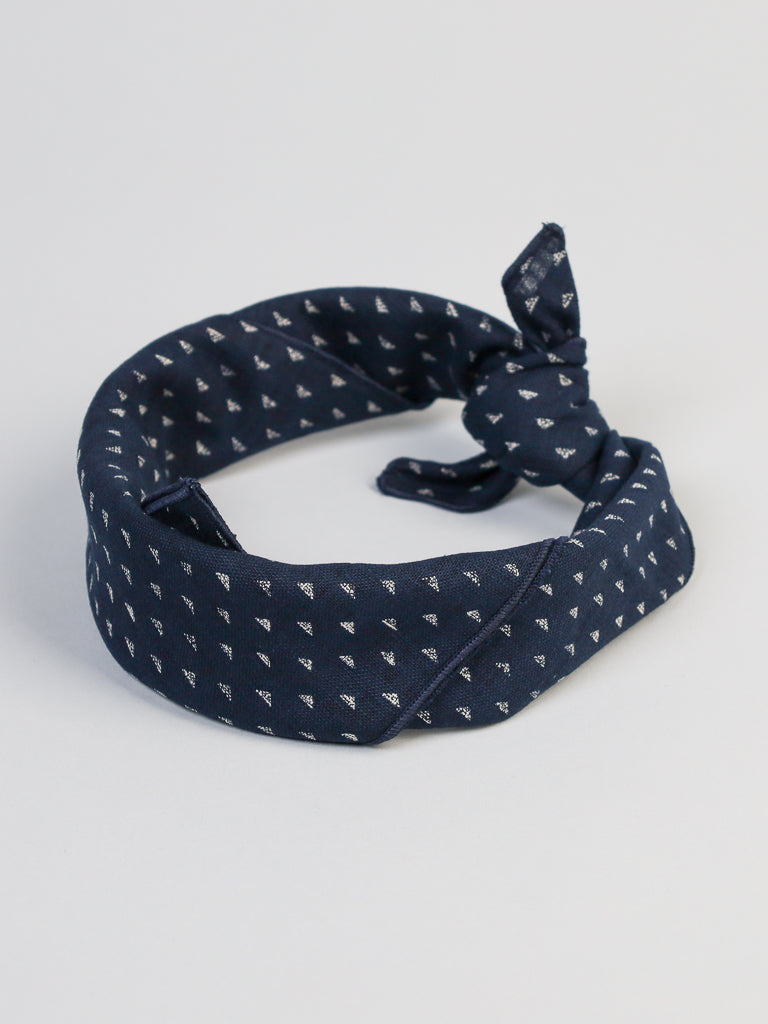 The Nara Japanese Geometric Bandana by ID Menswear is a navy blue headband with a small white triangular pattern, knotted at the front and set against an indigo background to resemble geometric mountains.