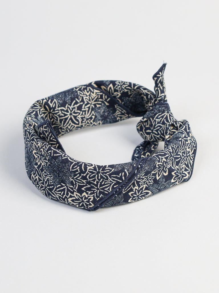 The Japanese Maple Leaf Bandana by ID Menswear, featuring a navy blue base and white floral pattern, is folded in a loop against a plain white background.