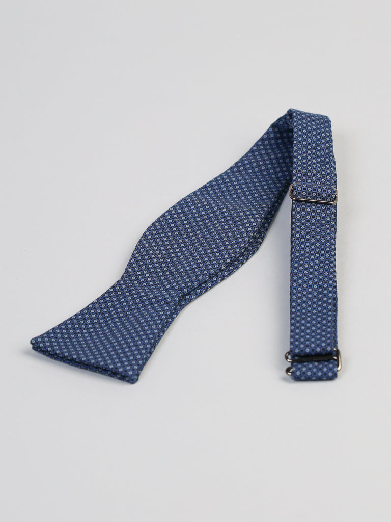 The Japanese Fleur Printed Bow Tie by ID Menswear is a blue, Japanese-printed cotton self-tie bow tie with an adjustable strap, handmade in Brooklyn and shown laid flat on a white surface.