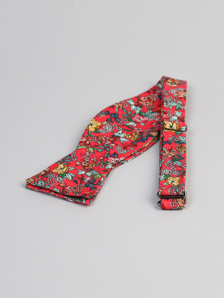 The Bouquet Cotton Bow Tie by ID Menswear is a self-tie accessory handcrafted in Brooklyn, featuring vibrant red cotton with yellow, green, and blue floral patterns—perfect for semi-formal occasions.