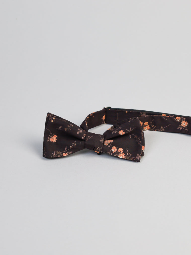 The ID Liberty of London Tana Lawn™ Elizabeth Cotton Bowtie by ID Menswear is crafted in Tana Lawn cotton, featuring a black base with a floral pattern of small peach and pink flowers on a light gray background.