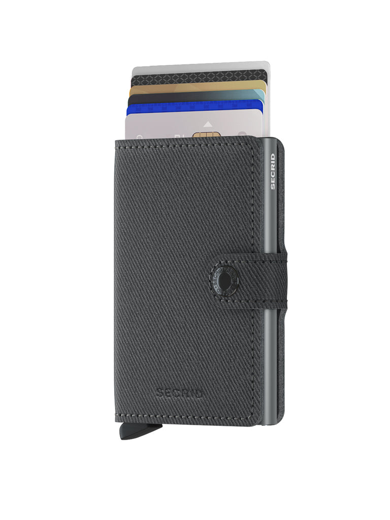 The Secrid Miniwallet Twist Twill Leather is a black textured compact wallet with a strap, RFID protection, button closure, and a visible card ejection tab, shown partially open to reveal stacked credit cards.