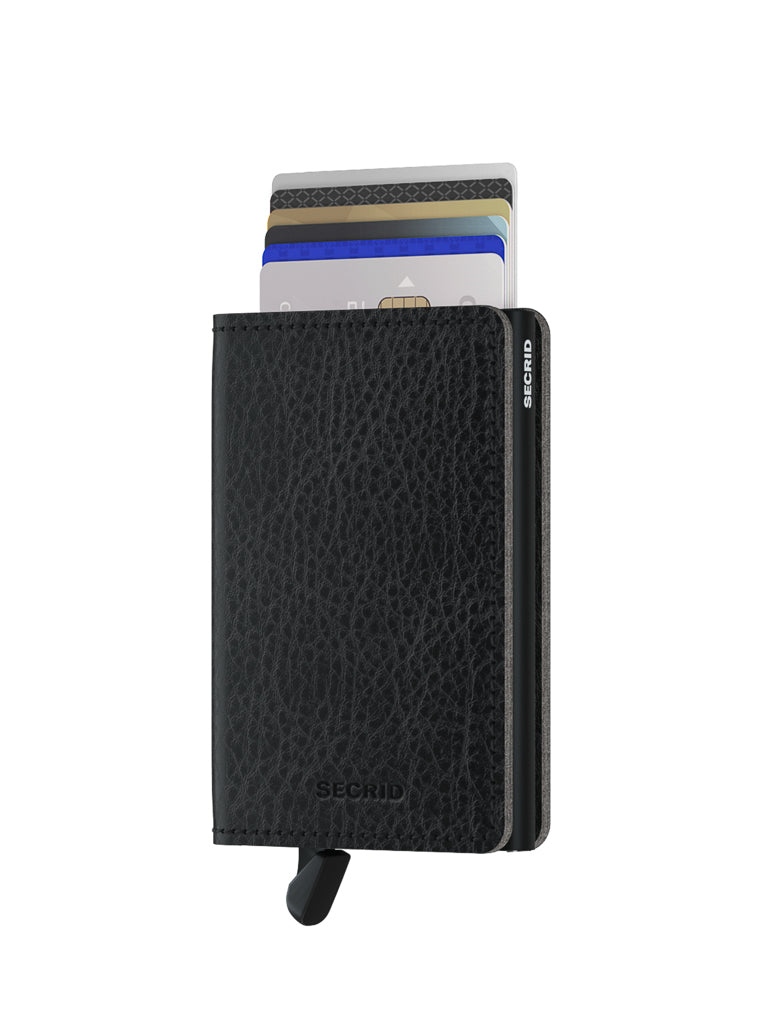 The Secrid Slimwallet Vegetable Tanned Leather, in textured black, stands upright on a white background with several credit cards partially visible and a small lever at the bottom left corner.