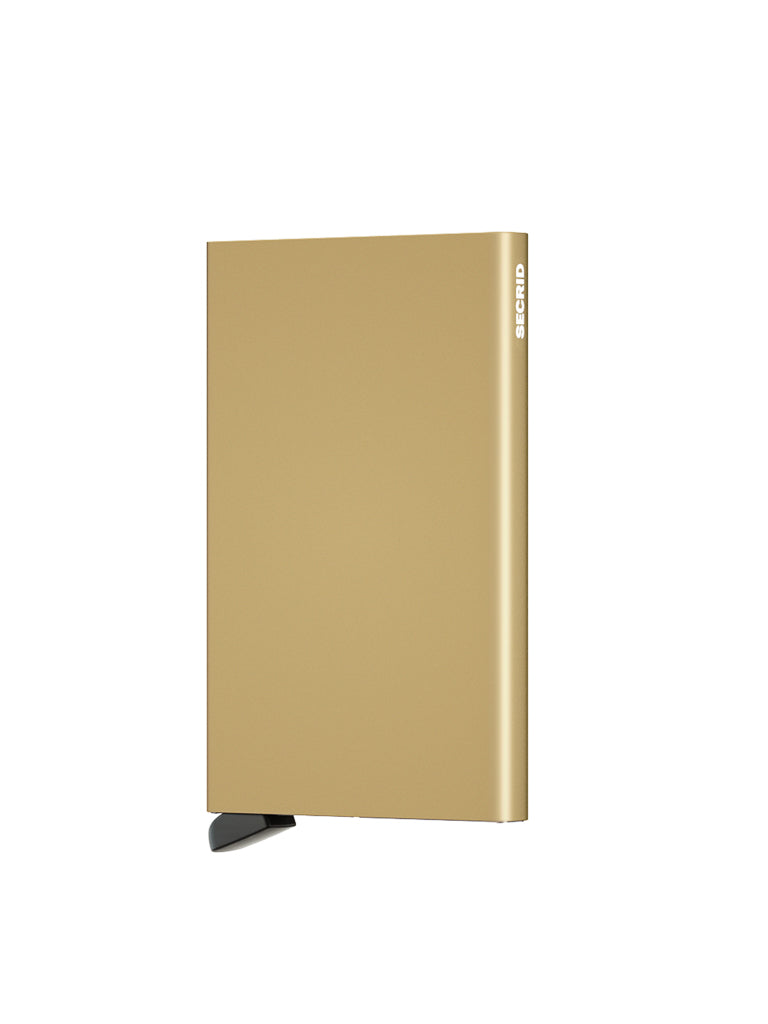 The Secrid Cardprotector Minimal Wallet is a slim, rectangular, gold-colored wallet resembling an external hard drive, with SECRID written vertically on the side and a small black stand. Shown against a plain white background.
