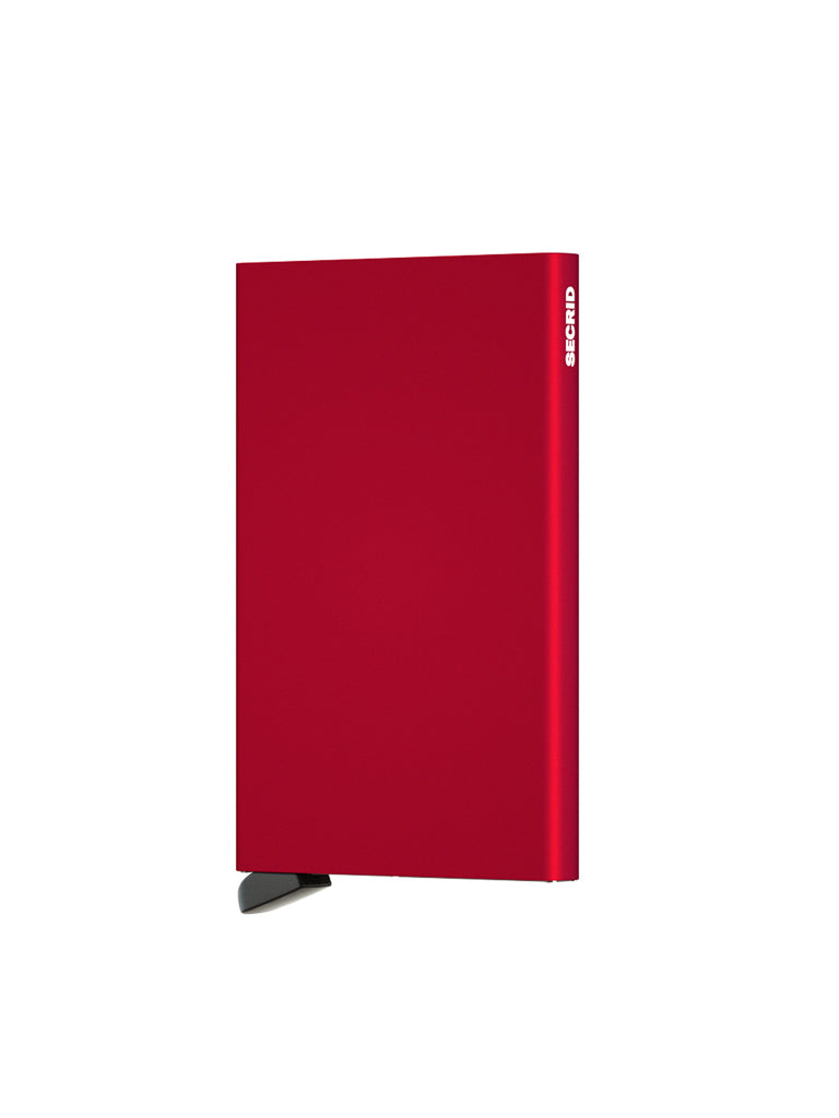 A slim, rectangular, red Cardprotector Minimal Wallet by Secrid stands upright on a small black base against a white background, featuring the brand name displayed vertically and inspired by minimal wallet design.