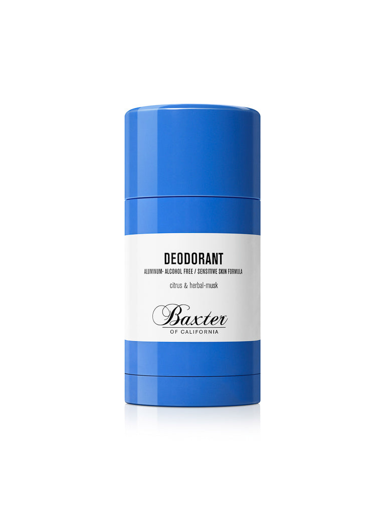 A blue cylindrical stick of Baxter Aluminium and Alcohol-Free Natural Deodorant features a white label with black text, formulated for sensitive skin and offering a fresh citrus and herbal-musk scent.