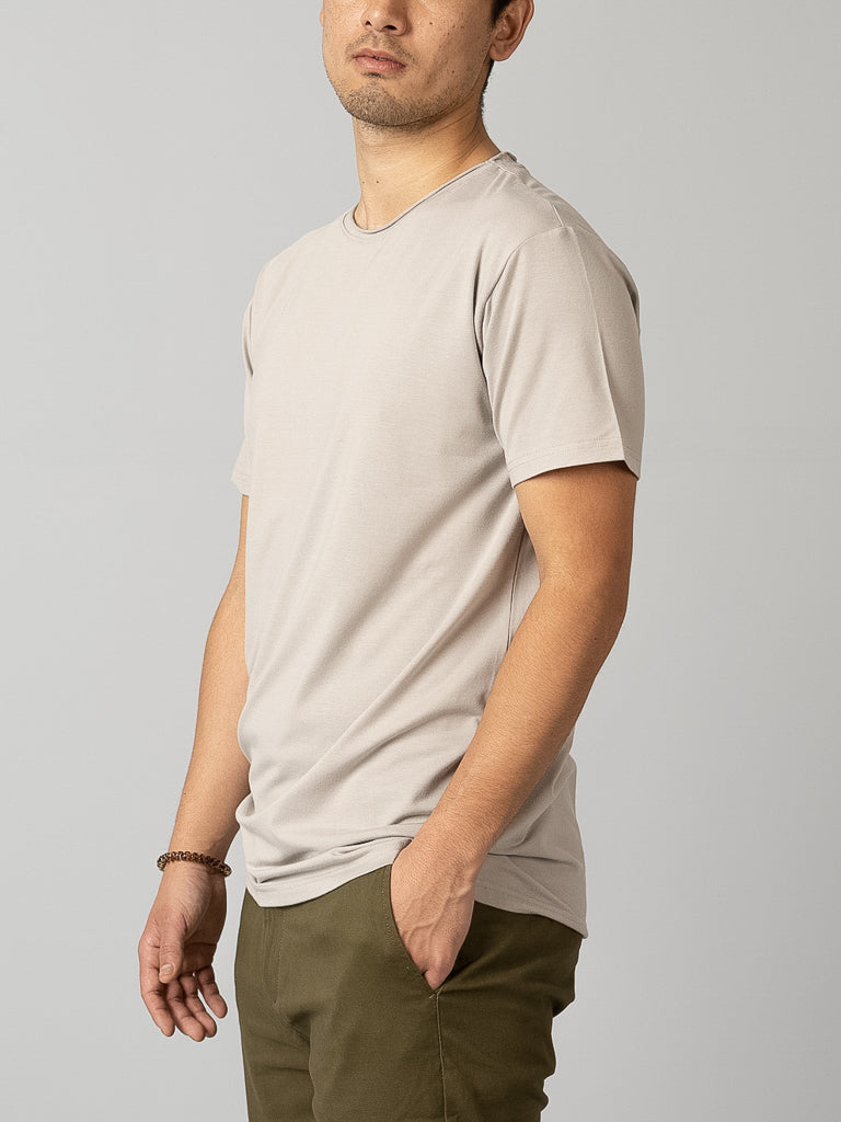 A person in an ID Menswear Bello Bamboo Blend Rolled Neck Tee stands against a plain background, wearing olive green pants. Their head is turned slightly to the right, with a bracelet on their left wrist.