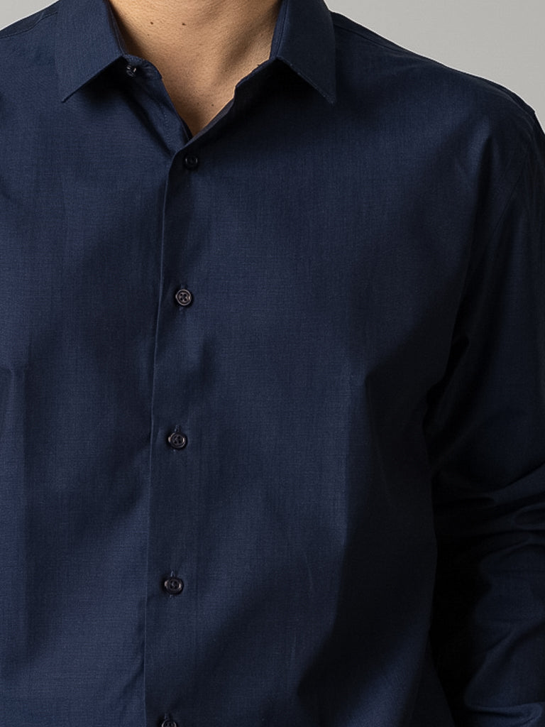 A person models the ID Menswear Cotton Dress Shirt in Slim Fit, dark navy blue with a collar and long sleeves, neatly pressed and covering the upper torso against a plain background.