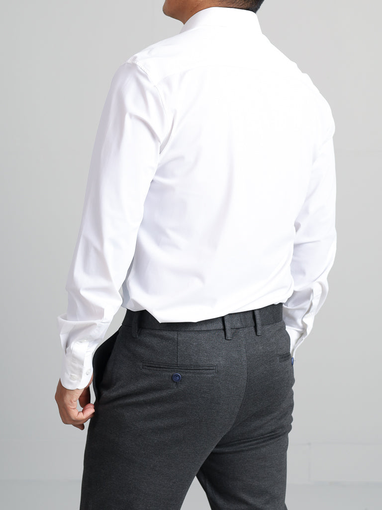 Seen from the back against a gray backdrop, a person wears an ID Menswear Axel 4-Way Stretch slim-fit white dress shirt and gray trousers, combining comfort and ease of movement for a polished look.