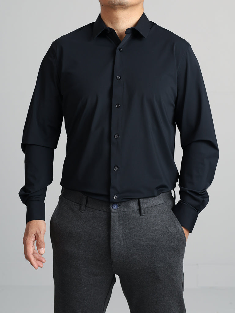 Someone is wearing an Axel 4-Way Stretch Dress Shirt from ID Menswear, featuring a slim-fit, long sleeves, and button-up style, paired with gray trousers against a light gray backdrop for comfortable wear.