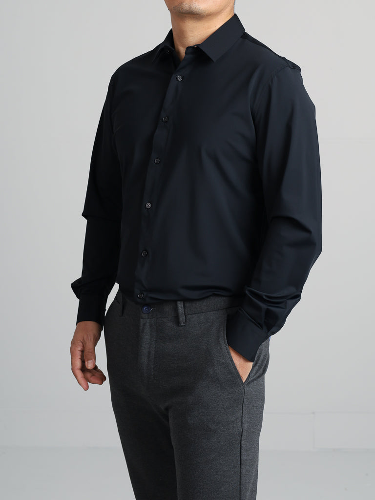 A person in a dark Axel 4-Way Stretch Dress Shirt by ID Menswear and gray pants stands against a light background. Their hand rests at their side, highlighting the 4-way stretch fabrics comfort.