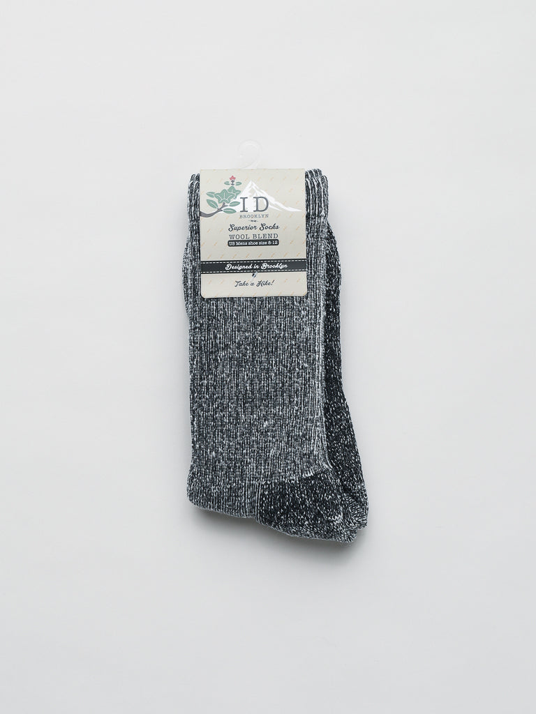 ID Menswears Merino Wool Blend Socks in gray and black speckle have a simple labeled top with text and a small plant graphic. The thick, textured material offers breathability and cold-weather comfort.