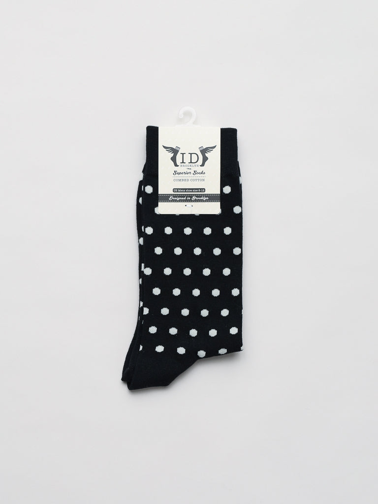 A pair of Polka Dot Graphic Socks in premium combed cotton, black with white polka dots, is neatly folded and secured with an ID Menswear tag featuring a display hook. Against a plain white background, these socks offer a comfortable design suitable for any occasion.