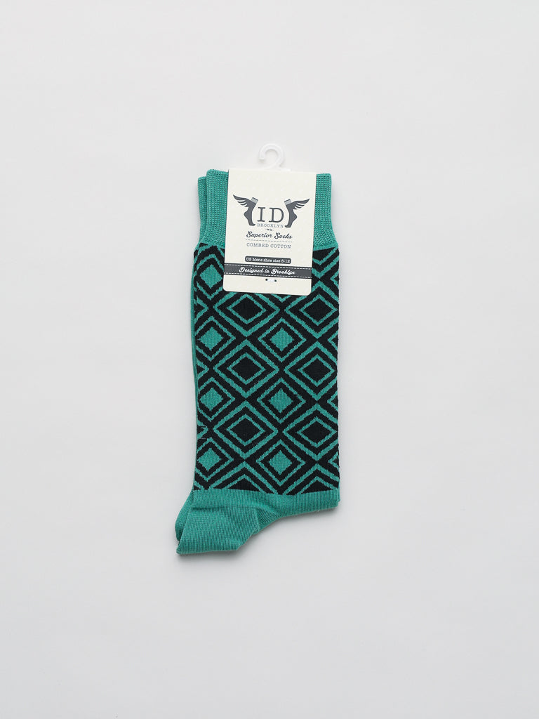 Folded against a plain white backdrop, the ID Smart Socks features teal socks with a black geometric diamond design. These premium combed cotton socks, known as Diamond Graphic Socks by ID Menswear, are designed to fit mens shoe sizes 8-12.