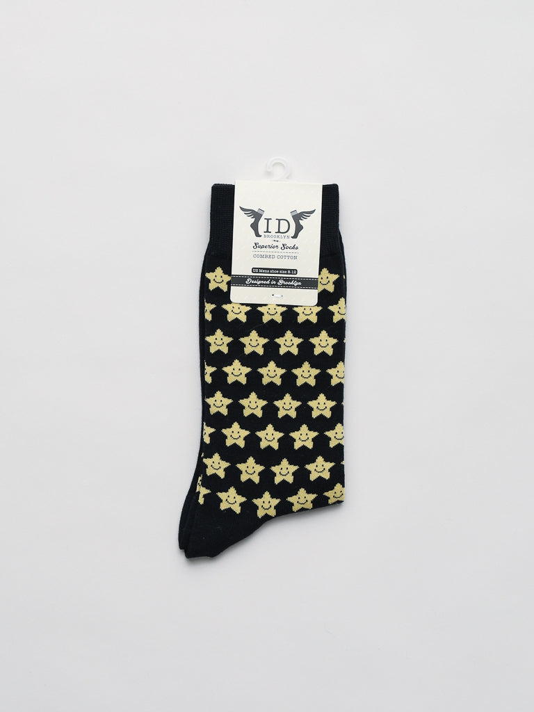 These black Twinkle Graphic Socks by ID Menswear feature a playful yellow sheriff badge pattern, making them an ideal gift. They are packaged with a label on a crisp white background.