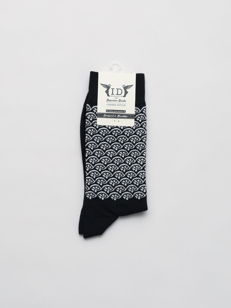 Neatly folded black socks from ID Menswear showcase a repeating white scallop pattern and come with a white label at the top highlighting the Lotus Graphic Socks. Crafted from combed cotton, these breathable socks also feature text for your convenience.