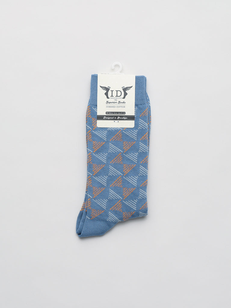 Dreamlines Graphic Socks by ID Menswear, made from breathable blue combed cotton, feature a geometric brown and white diamond pattern. Displayed on a light background, they come packaged with a label detailing the brand ID and more.