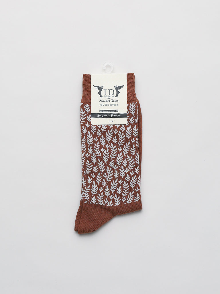 Brown socks featuring white intricate fern patterns, neatly folded on a white background. The label at the top subtly shows the ID Menswear brand, suggesting these are Flora Graphic Socks—premium quality that offer comfort and breathability.