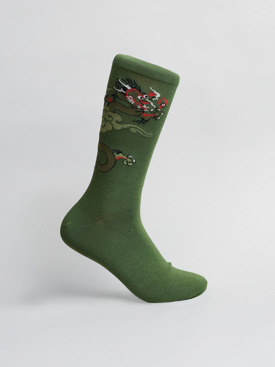 ID Menswears Dragon Graphic Socks, made of premium cotton, feature a vibrant dragon design in red, orange, and black on green. Displayed upright against a light gray background, they offer an artistic flair with their bold motif.