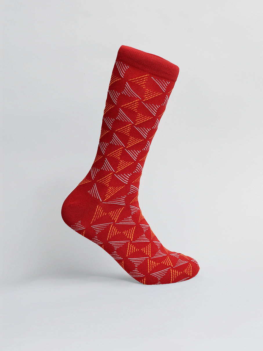 The Dreamlines Graphic Sock by ID Menswear is a single red sock crafted from breathable combed cotton, showcasing an abstract geometric pattern in orange and pink on a light gray background.