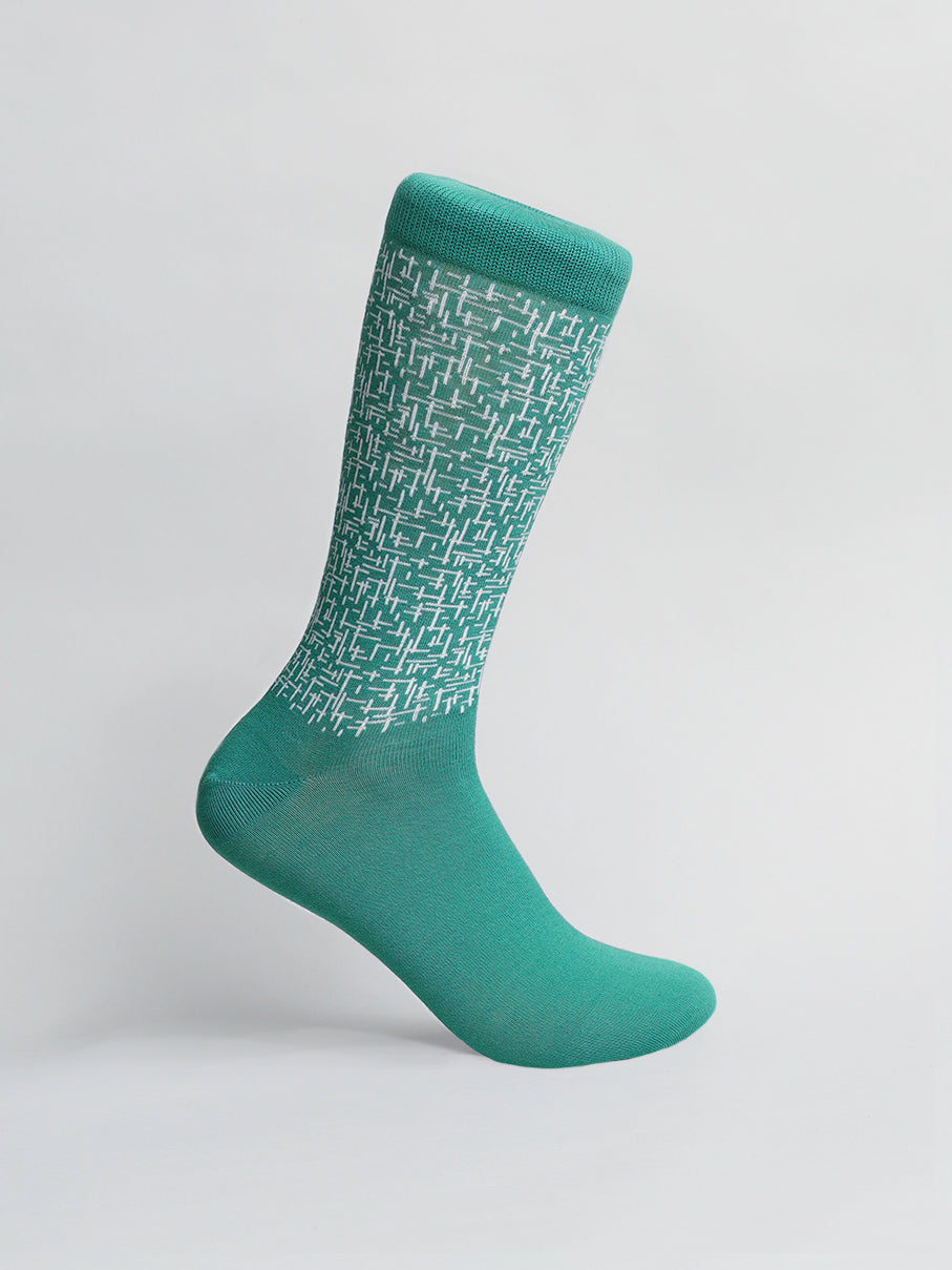 A lone Urban Graphic Sock from ID Menswear, featuring a white geometric pattern on its green calf area, is elegantly displayed against a plain white background. Made from combed cotton, its a vibrant and contemporary addition to any sock collection.