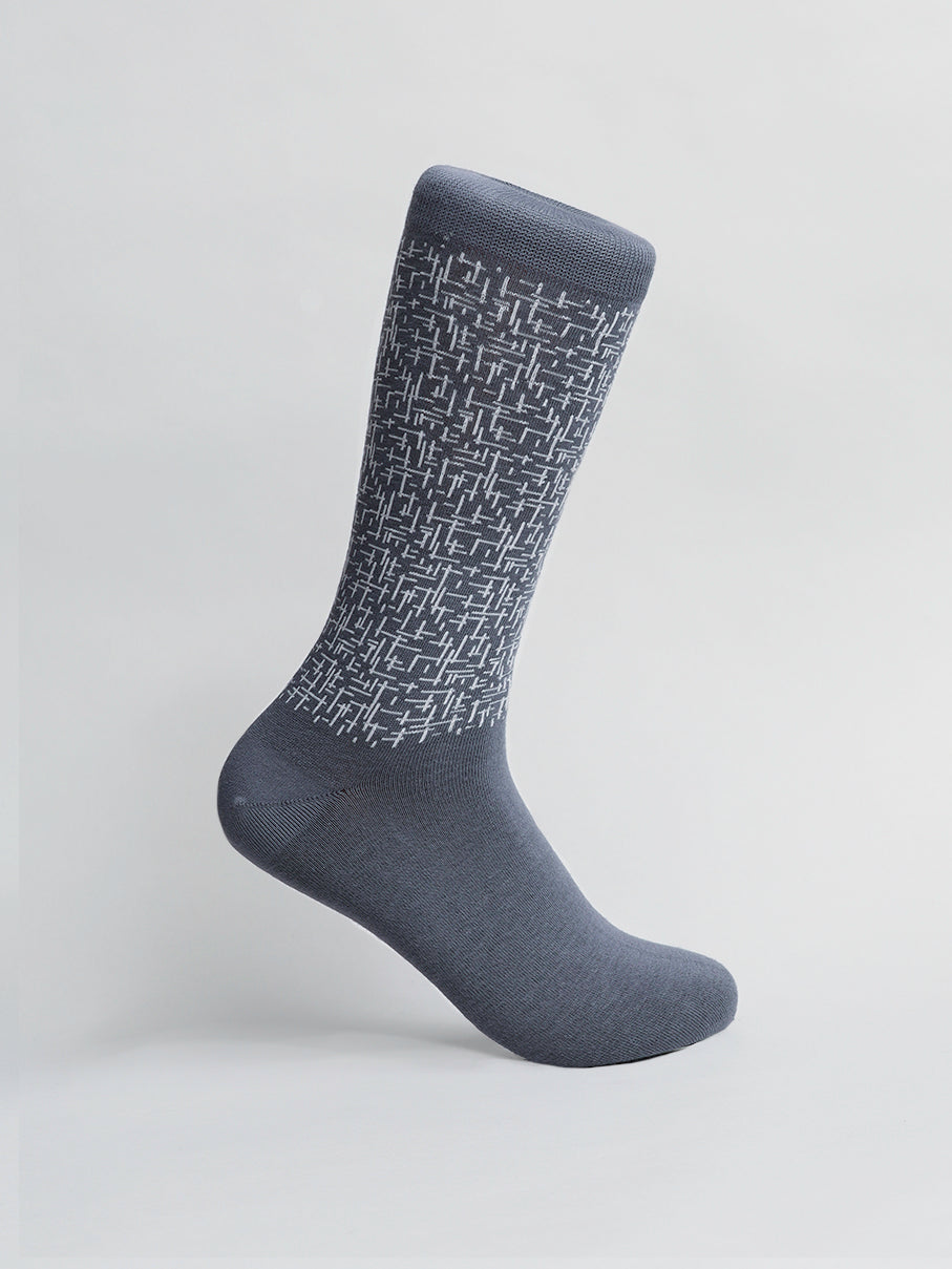 Urban Graphic Socks by ID Menswear feature a white raised geometric pattern on soft combed cotton, offering a mid-calf length. The modern design stands out against its light gray backdrop, showcasing its textured style and solid color.