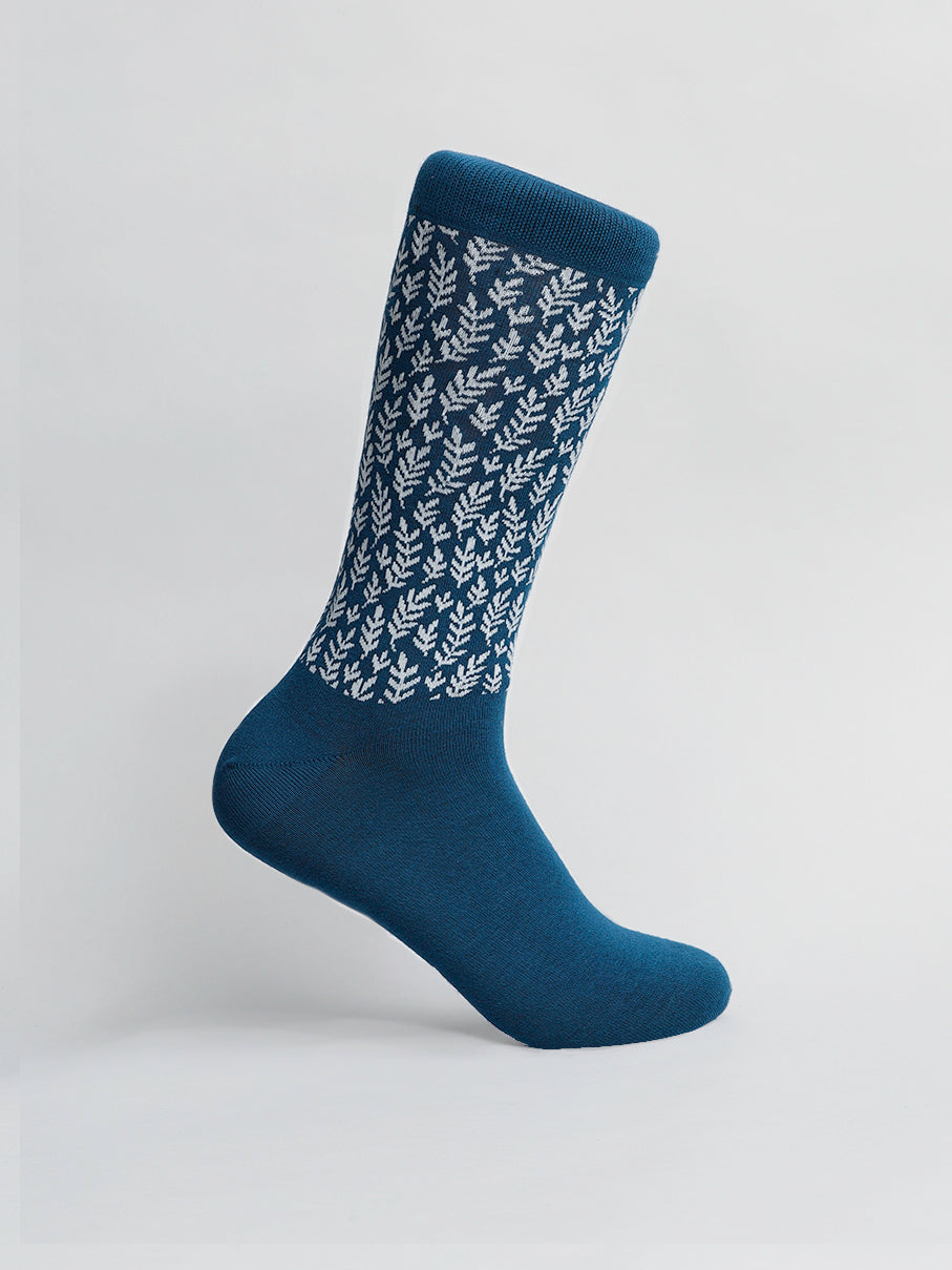 The Flora Graphic Sock by ID Menswear is a single blue sock with a white leaf pattern made of premium combed cotton, displayed upright against a plain background, highlighting its comfortable and breathable design.
