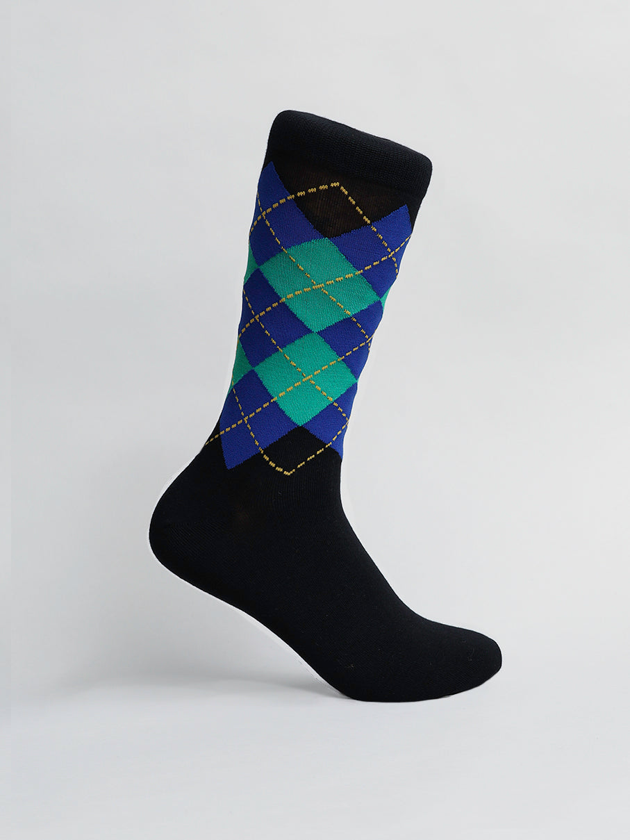 Against a plain white backdrop, an ID Menswear Argyle Graphic Socks showcases its intricate blue, green, and yellow argyle pattern on a black combed cotton sock displayed at an angle.
