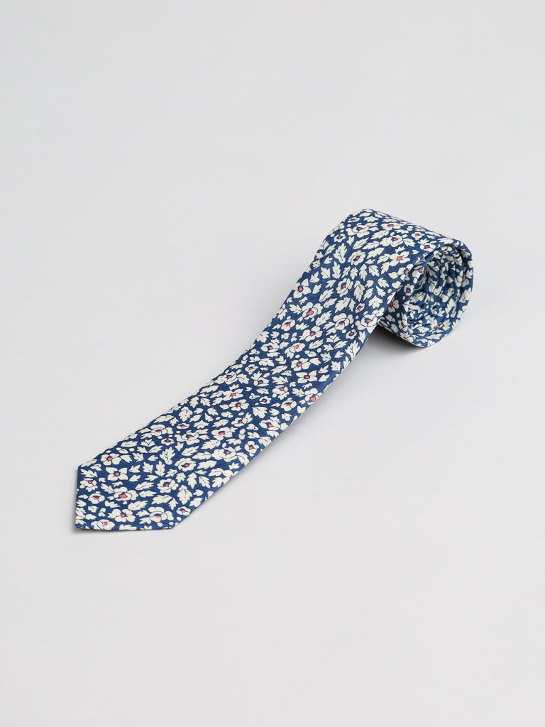 The Liberty of London Tana Lawn™ Feather Tie by ID Menswear is handmade in Brooklyn from soft cotton and features a blue base with a white and red floral pattern, displayed on a plain, light background.