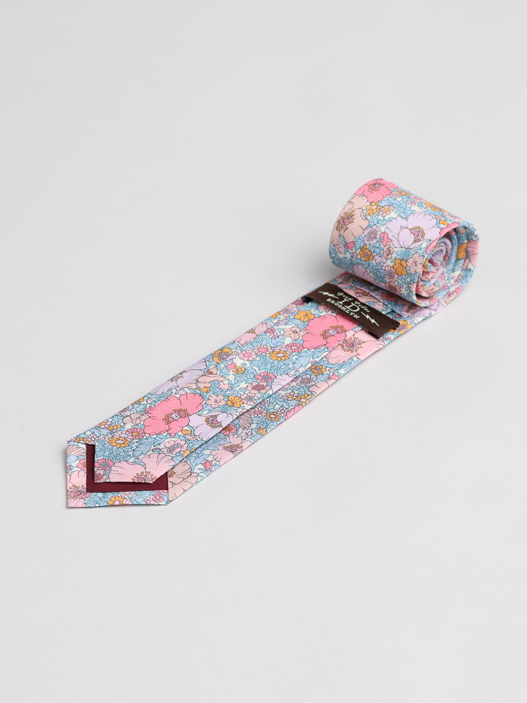The ID Menswear Liberty of London Tana Lawn™ Pink Lawn Tie features a vibrant floral print in pink, blue, and white on soft cotton, shown rolled up against a plain white background.
