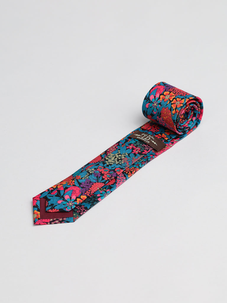 The ID Menswear Liberty of London Tana Lawn™ Ciara Tie showcases a vibrant red, pink, blue, and orange floral pattern on luxurious cotton, displayed against a plain white background.