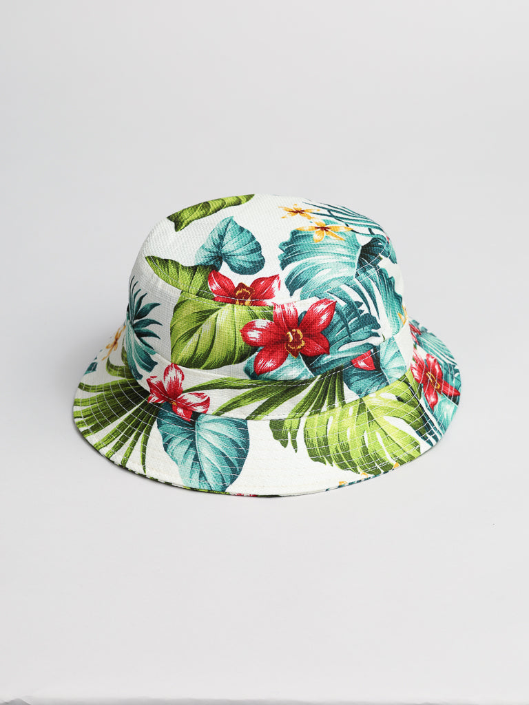 The ID Hawaii Bucket Hat by ID Menswear, made from Japanese cotton, features a vibrant tropical design of green palm leaves and red flowers on a white background. Perfect for sunny day adventures!.
