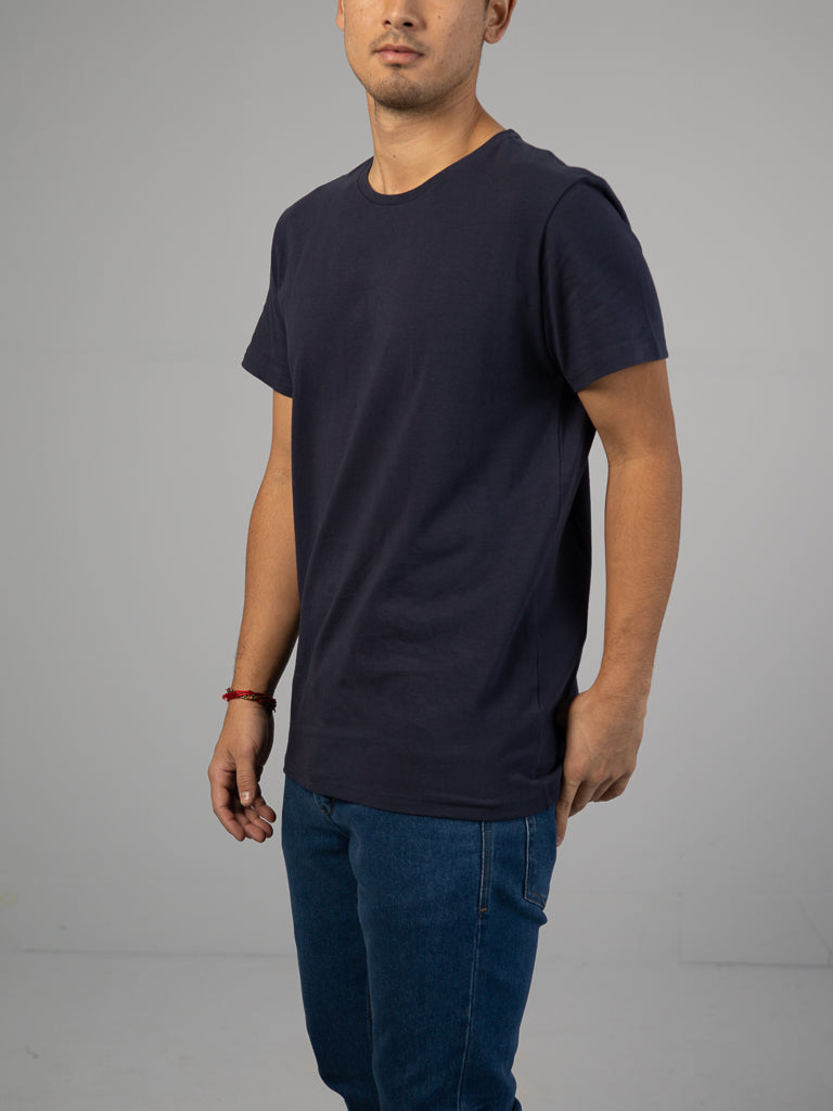 Someone in an ID Menswear Form Crew Neck Tee and blue jeans poses against a neutral background, obscuring their face.