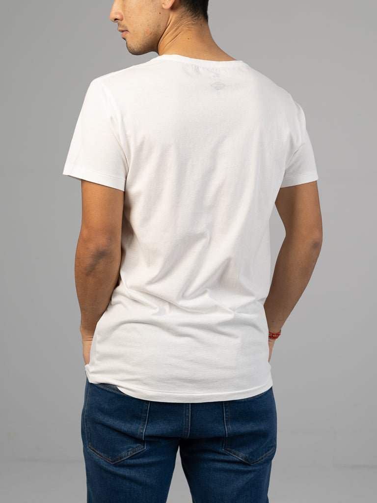 A person in a classic fit Legacy Organic Cotton Tee by ID Menswear and blue jeans stands with their back to the camera, hands casually in pockets against a light gray backdrop, embracing a timeless, vintage look.