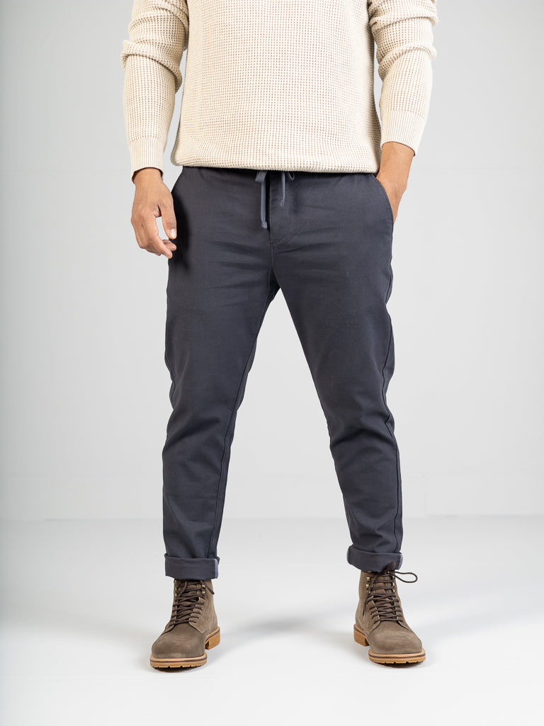 A person in an ID Menswear cream sweater and Kent Drawstring Canvas Pant by ID Menswear, styled with hands in pockets, pairs it with light brown boots featuring noticeable tread soles against a plain white background.