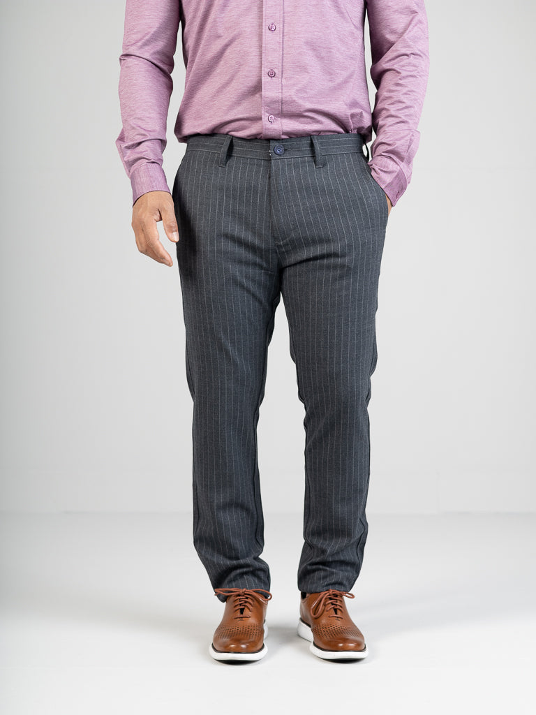 A person in a purple button-up shirt, gray pinstripe Hudson Wool Blend Pin Stripe Pant by ID Menswear, and brown dress shoes stands against a plain background, hands casually in pockets.