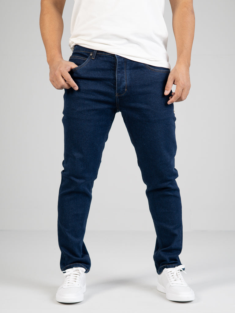 A person poses with one hand in their pocket, wearing a white T-shirt and white sneakers, highlighting the casual style of ID Menswears Ganbaru Stretch Jean against a plain background.