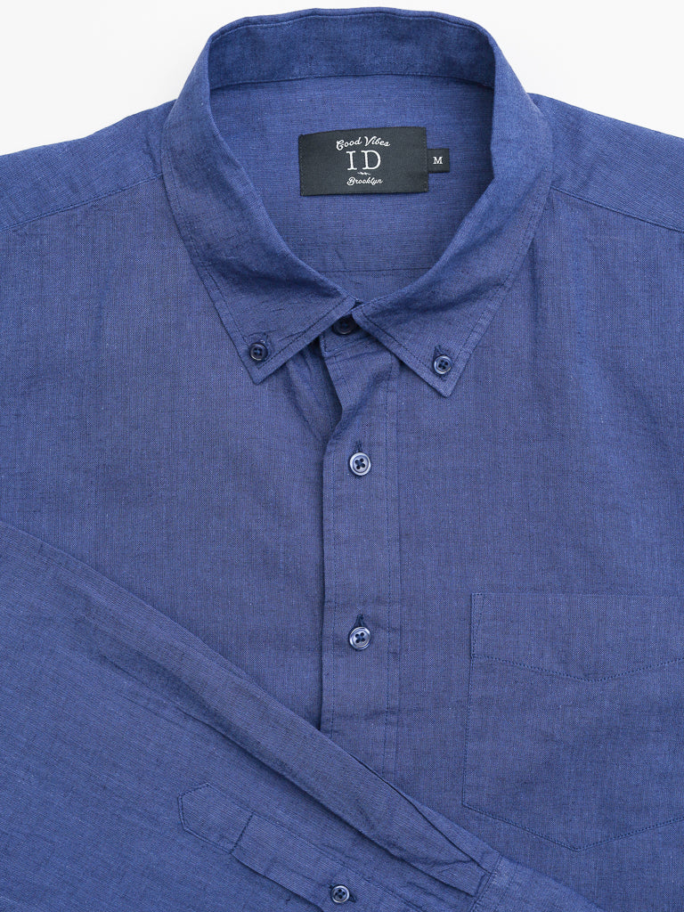 A neatly folded Marcus Linen Blend Button Down Shirt in blue, featuring a front pocket and textured appearance from a linen-cotton blend. It has a button-down collar for style and the label inside reads Good Vibes by ID Menswear, size M.