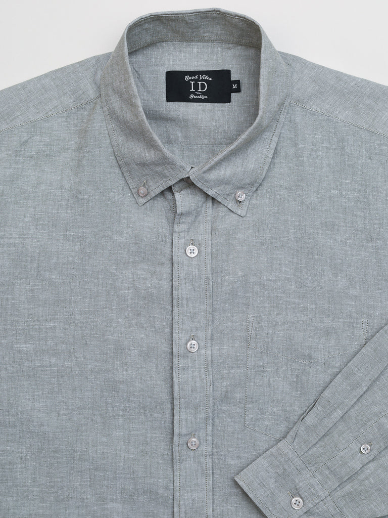 Close-up of the Marcus Linen Blend Button Down Shirt from ID Menswear, featuring a gray regular-fit, button-down collar, subtle texture, white buttons, and a front left chest pocket. A black label inside the collar displays brand and size. Neatly laid on a flat surface.