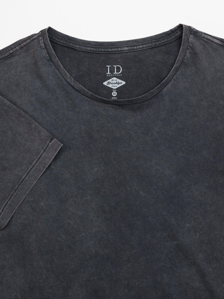 The Legacy Organic Cotton Tee by ID Menswear is a classic fit, faded black t-shirt featuring a visible round neck and sleeves. Made from organic cotton, the inside label details size and brand, while the fabrics slightly worn texture offers a vintage look against a plain white background.