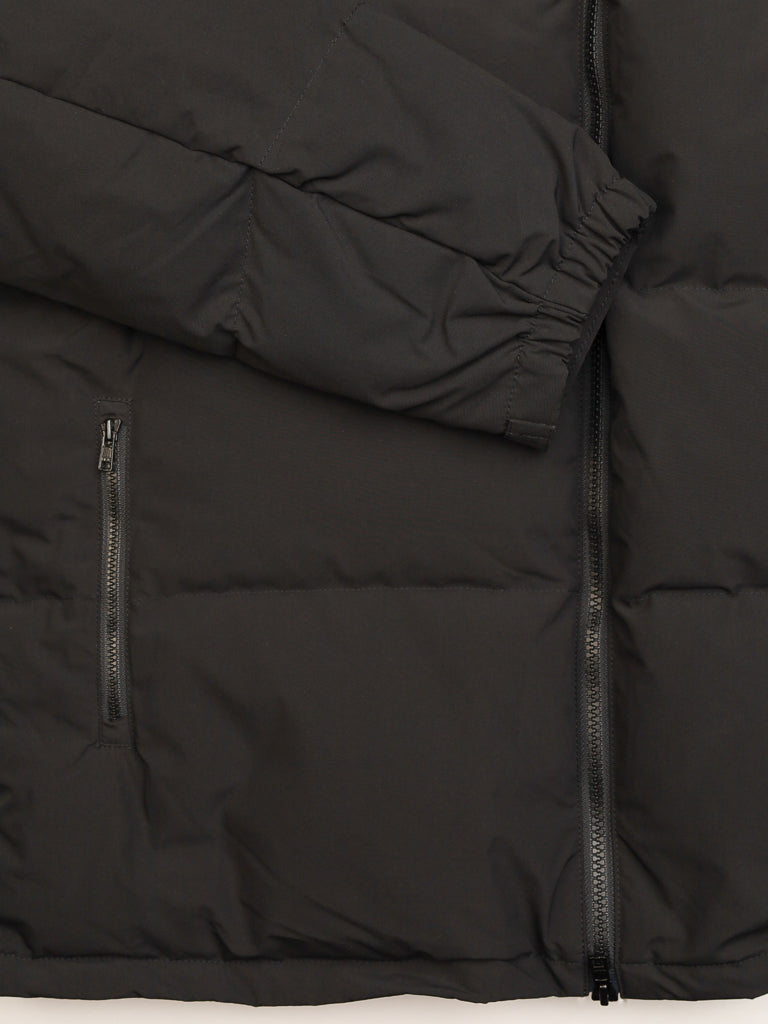 Close-up of the ID Menswear Arctic Black Puffer Down Jacket shows a zippered side pocket, front zipper, and elastic-cuffed sleeve, highlighting its quilted texture, detailed stitching, and water-resistant finish.