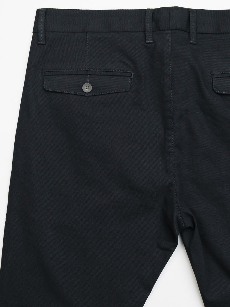 The Wythe Twill Stretch Chino from ID Menswear are dark-colored, slim-fit pants shown from the back, featuring belt loops, two button-closure rear pockets, and visible stitching. Made from durable cotton twill, theyre ideal for casual wear.