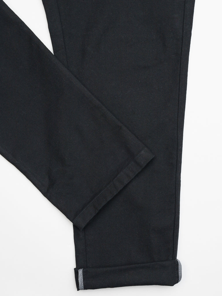 The Kent Drawstring Canvas Pant by ID Menswear features a black, slim-fit, mid-rise design with a single folded cuff. Made from smooth cotton canvas, it is laid on a plain white background with a neatly sewn hem.