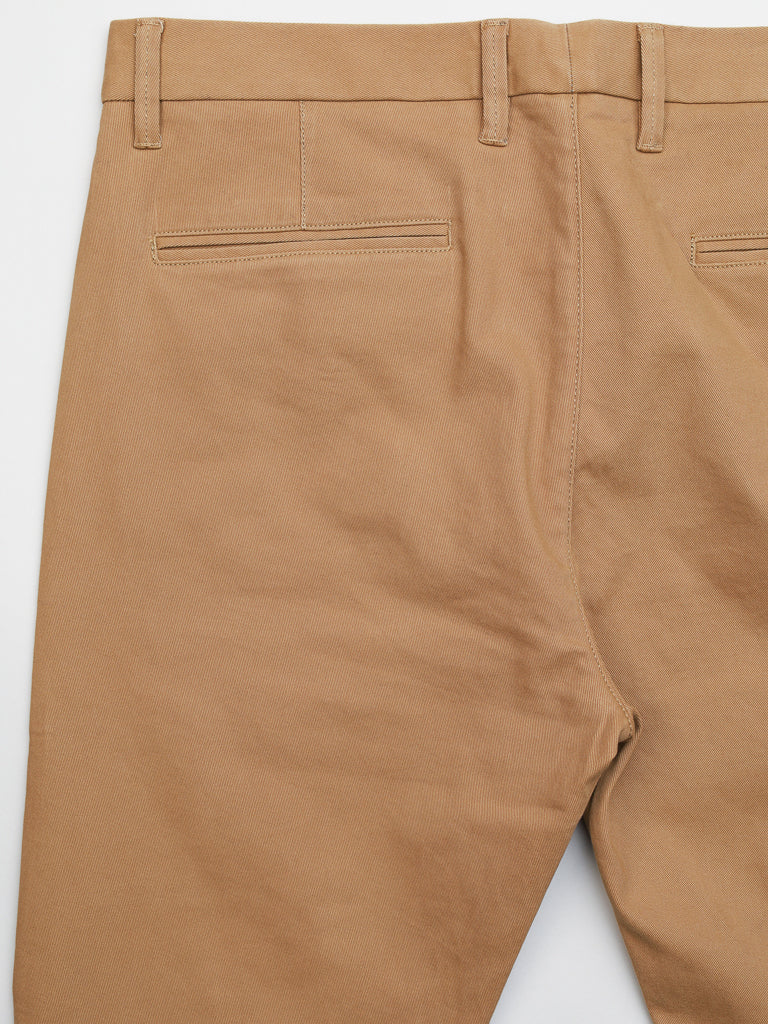 A close-up of the tan, mid-rise ID Menswear Banker Twill Stretch Chino shows the back section featuring regular slim-fit design with sturdy fabric, two welt pockets without visible buttons, and clear stitching around the pockets and waistband.