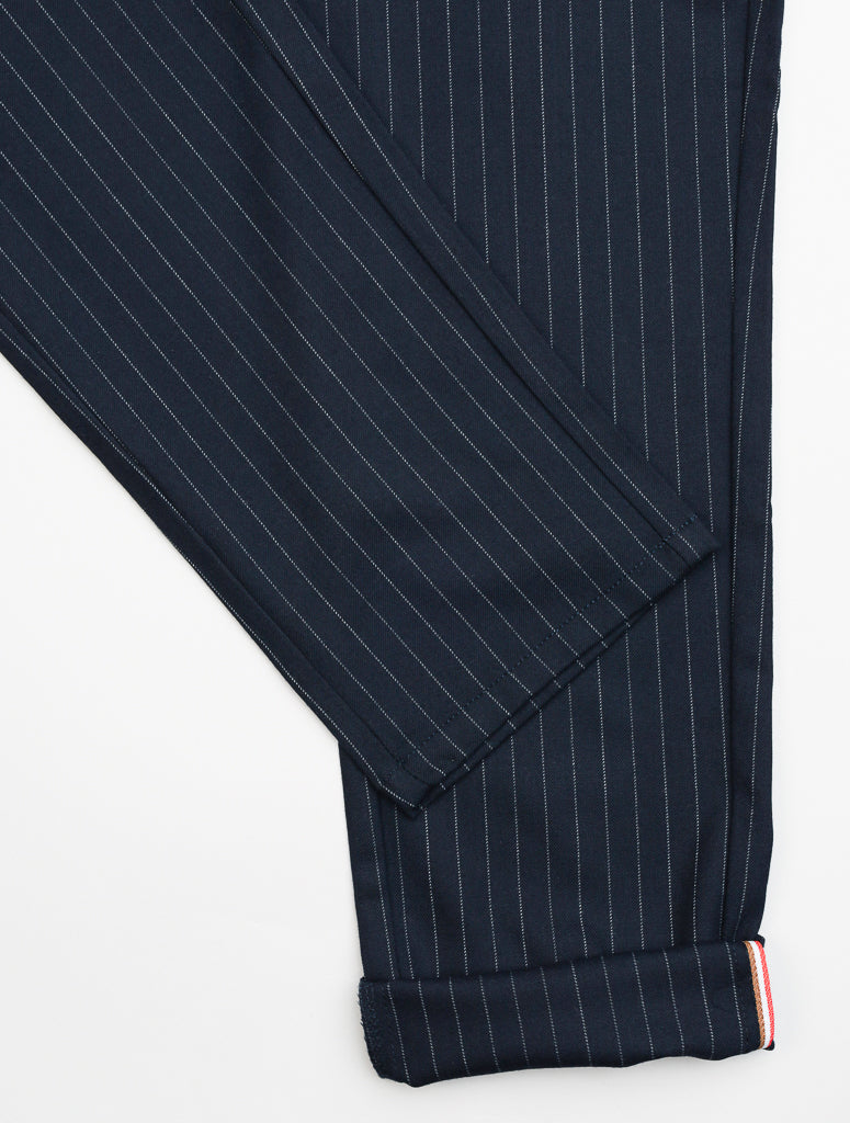 Close-up of dark blue Hudson Wool Blend Pin Stripe Pant by ID Menswear, featuring thin pinstripes that create a formal look. Crafted in a premium wool blend, they offer a mid-rise slim fit with folded hems and a small striped tab on the cuff.