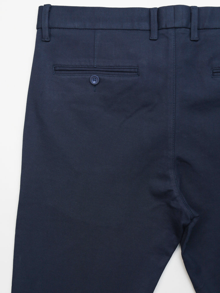 The Manhattan 4-way Stretch Dress Pant by ID Menswear features a slim-fit in navy blue, with a buttoned back pocket and belt loops for business casual style. The wrinkle-resistant fabric is smooth-textured, displayed flat on a white surface.