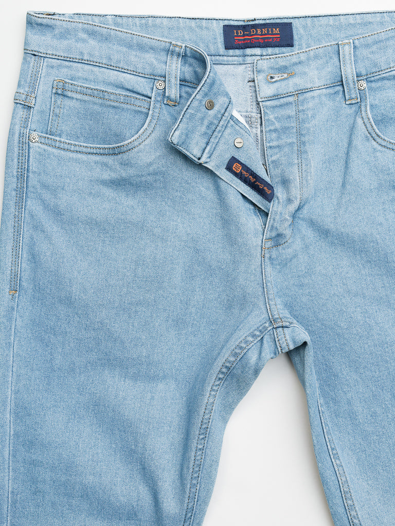 The Ganbaru Stretch Jean by ID Menswear features light blue denim in a slim-tapered fit with a partially undone button and zipper, revealing the inner waistband label. Made from durable cotton twill, it includes classic five-pocket styling and visible stitching.