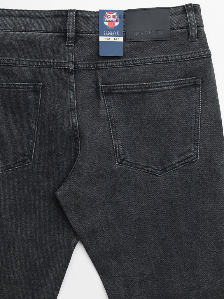 Back view of Ganbaru Stretch Jean by ID Menswear showcases a slim-tapered fit in dark gray denim, featuring two pockets and a black waist label. A blue and white size tag is attached to the waistband.